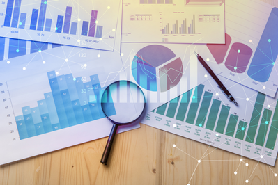 magnifying glass lying on graphs showing trends