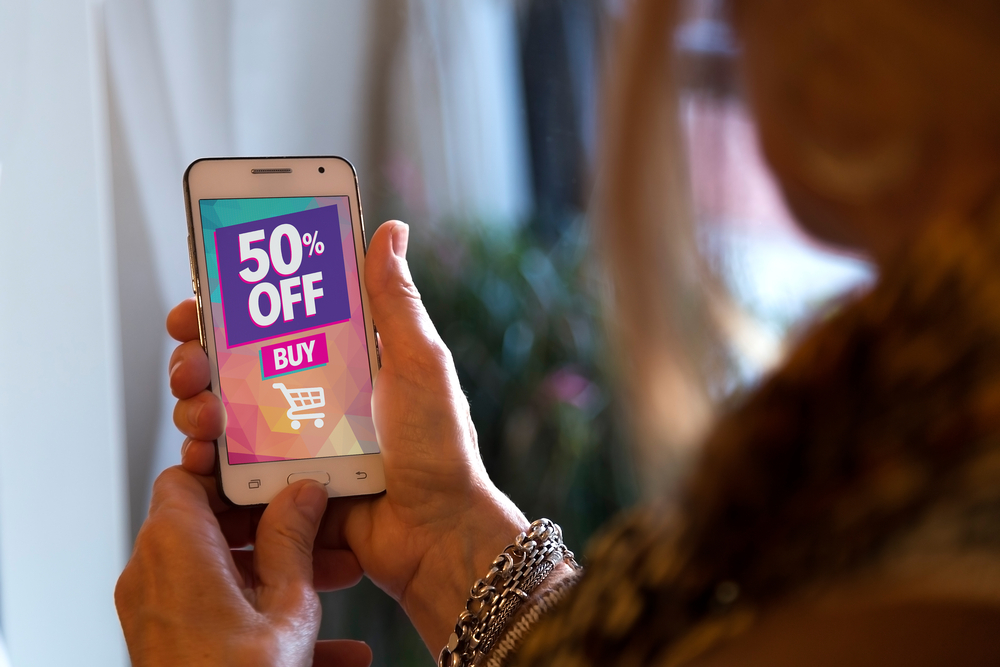 woman looking at 50% off promo on smartphone