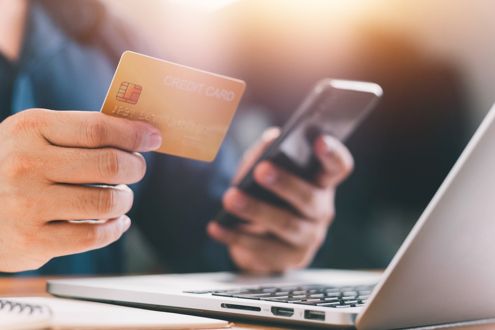 hand holding credit card while other enters payment information on smartphone